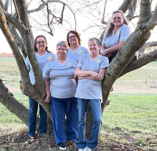 The Bailey sisters smile for the camera while posing in front of a tree